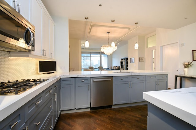 kitchen featuring pendant lighting, sink, gray cabinetry, stainless steel appliances, and tasteful backsplash