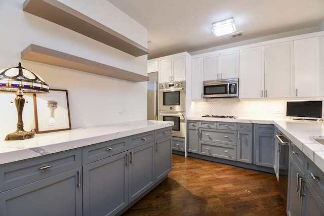 kitchen with stainless steel appliances, gray cabinetry, white cabinets, and backsplash