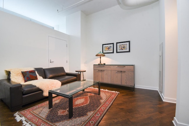 living room with a high ceiling and dark wood-type flooring