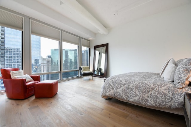 bedroom featuring access to exterior, beam ceiling, and light hardwood / wood-style floors