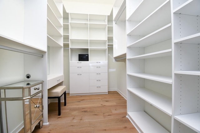 walk in closet with light hardwood / wood-style flooring