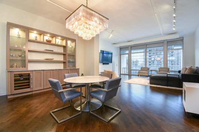 dining room featuring an inviting chandelier, track lighting, beverage cooler, and dark hardwood / wood-style flooring