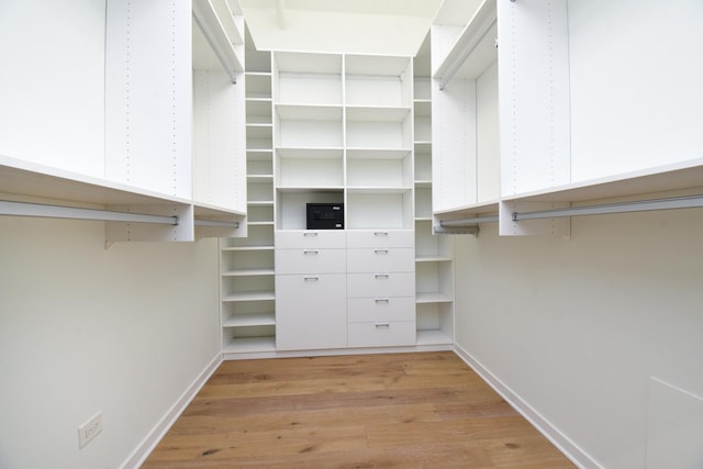 walk in closet with light hardwood / wood-style floors