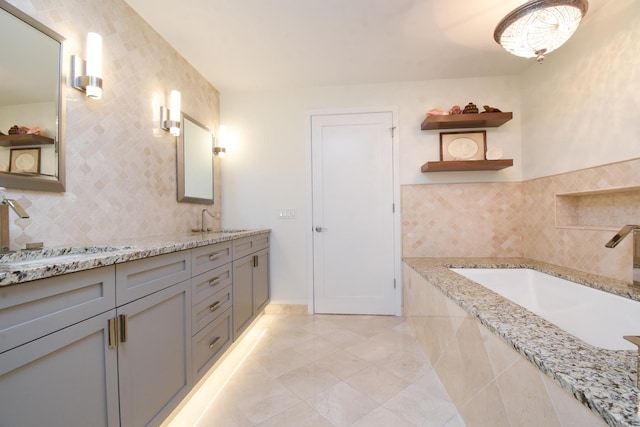 bathroom with vanity, tiled bath, tile patterned floors, and backsplash