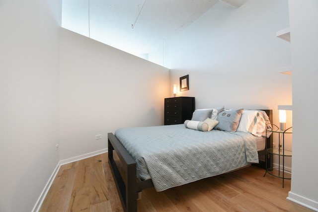 bedroom with a high ceiling and hardwood / wood-style floors