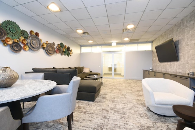 living room with a drop ceiling, a wealth of natural light, and carpet flooring