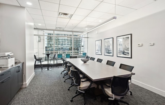 office space featuring dark colored carpet, a paneled ceiling, and a wall of windows