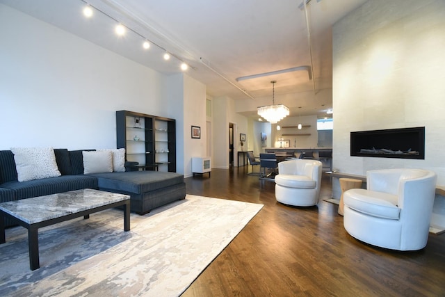 living room featuring an inviting chandelier, track lighting, and dark hardwood / wood-style flooring