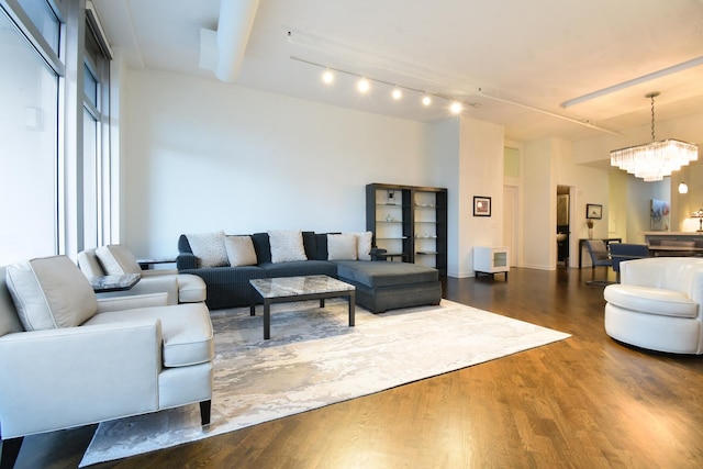 living room featuring rail lighting, dark hardwood / wood-style floors, and a notable chandelier