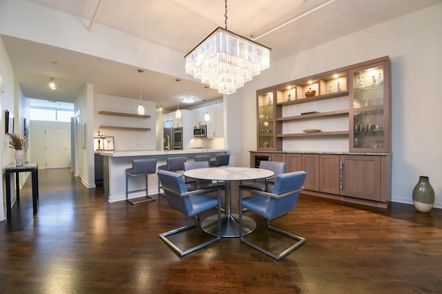 dining area with dark wood-type flooring and an inviting chandelier