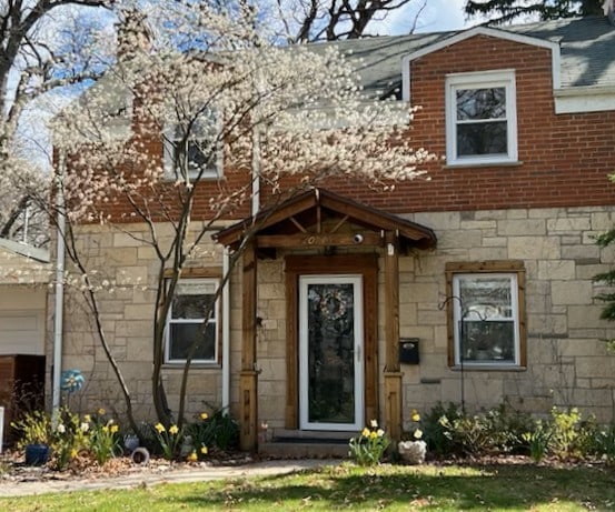 view of exterior entry with a garage, stone siding, and brick siding