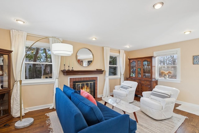 living area featuring a healthy amount of sunlight, a fireplace, baseboards, and wood finished floors