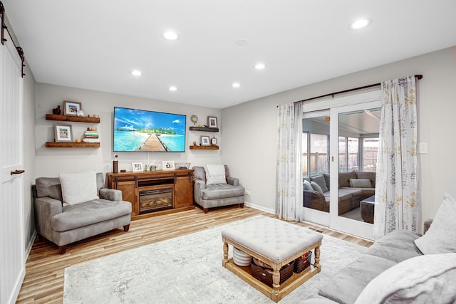 living room with a barn door and light hardwood / wood-style flooring