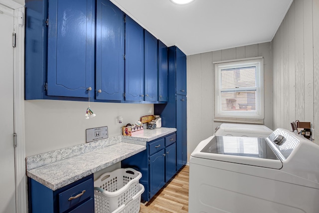 washroom with cabinets, separate washer and dryer, wooden walls, and light hardwood / wood-style floors