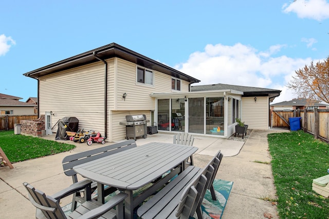 rear view of house featuring a sunroom, a lawn, and a patio area