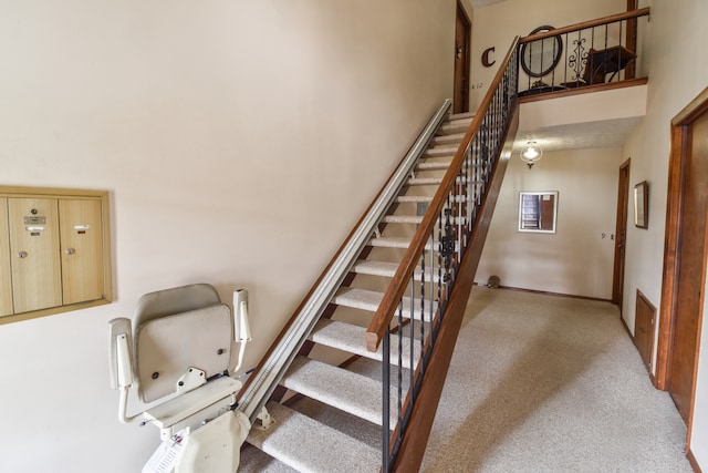 stairway with carpet floors and a high ceiling