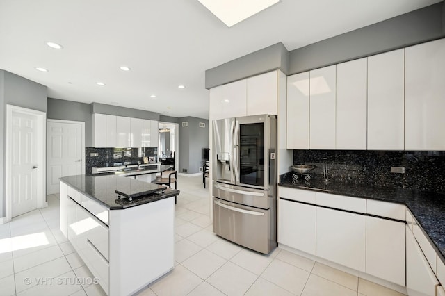 kitchen featuring white cabinetry, dark stone counters, and stainless steel fridge