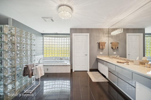 bathroom featuring tile patterned floors, tiled tub, vanity, and a wealth of natural light