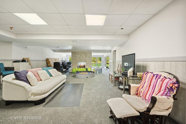 carpeted living room with a paneled ceiling and wooden walls