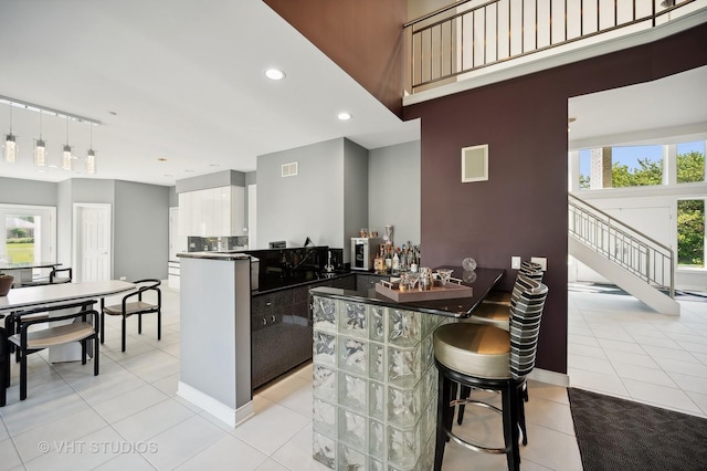 kitchen with decorative light fixtures, a wealth of natural light, kitchen peninsula, and white cabinets