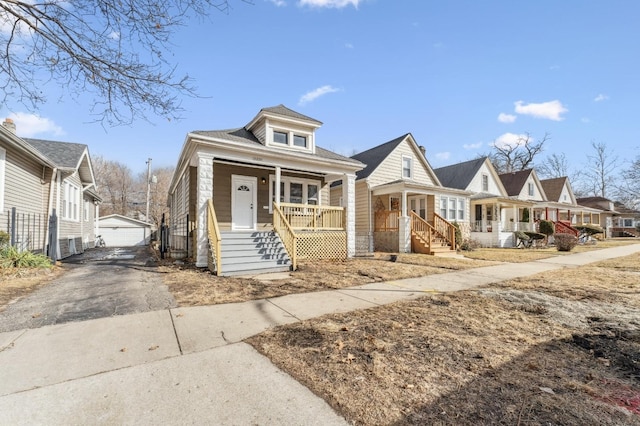 view of front of property with covered porch, a detached garage, an outdoor structure, and a residential view