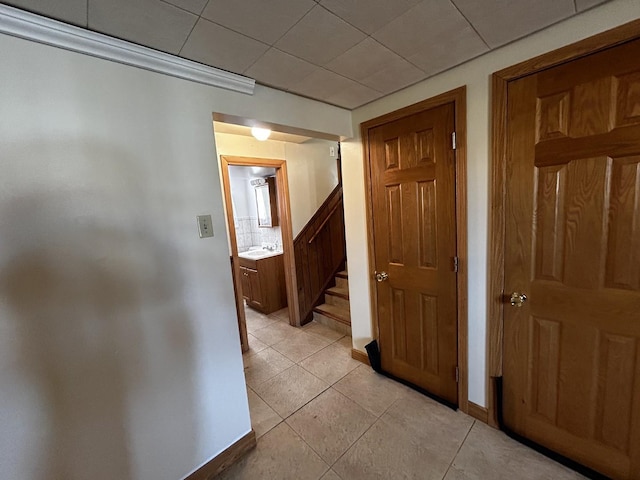 corridor featuring light tile patterned flooring, a sink, stairway, and baseboards