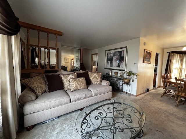 living room featuring baseboards, stairway, and light colored carpet