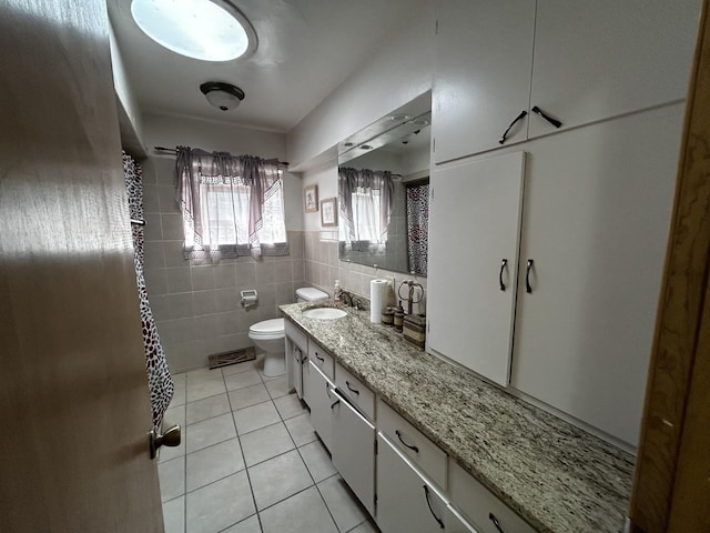 bathroom featuring a wainscoted wall, tile walls, toilet, vanity, and tile patterned floors