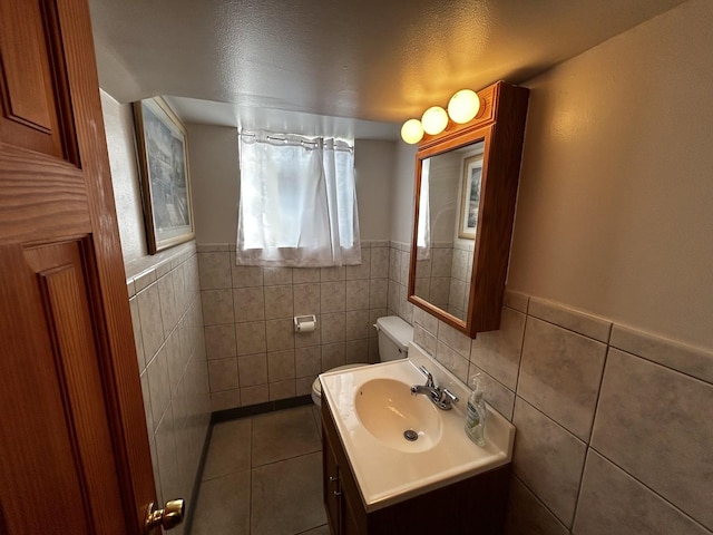 half bath featuring tile patterned flooring, tile walls, and vanity