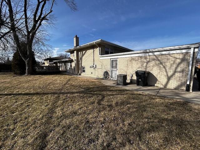 view of side of property featuring a yard, a chimney, and brick siding