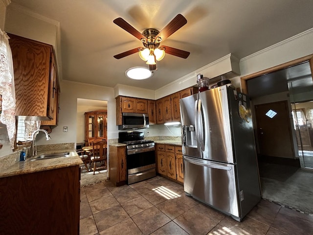 kitchen featuring stainless steel appliances, a sink, a ceiling fan, ornamental molding, and brown cabinetry