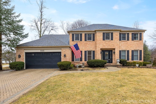 view of front of house featuring brick siding, a front lawn, roof with shingles, decorative driveway, and an attached garage