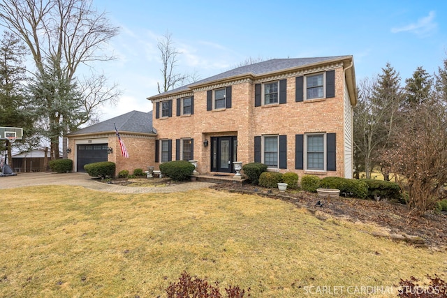 colonial home with brick siding, an attached garage, driveway, and a front yard