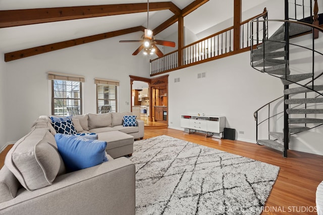 living area with stairs, wood finished floors, visible vents, and a ceiling fan