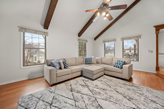 living room with beamed ceiling, wood finished floors, visible vents, and a wealth of natural light