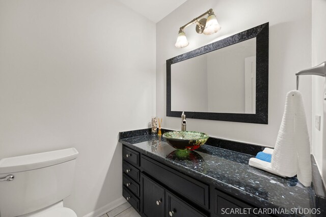 half bath featuring baseboards, toilet, and vanity
