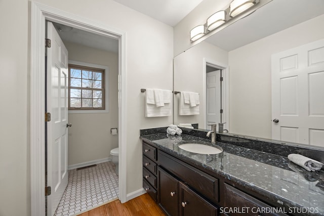 bathroom featuring vanity, wood finished floors, visible vents, baseboards, and toilet