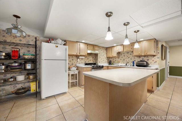kitchen with light brown cabinets, under cabinet range hood, light countertops, light tile patterned flooring, and white appliances