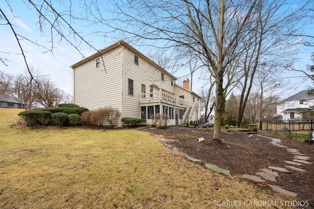 rear view of property with stairway, fence, a lawn, and a sunroom