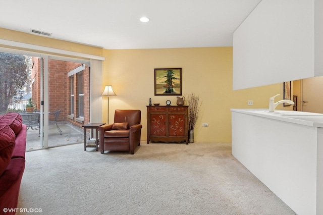 living area with sink and light carpet