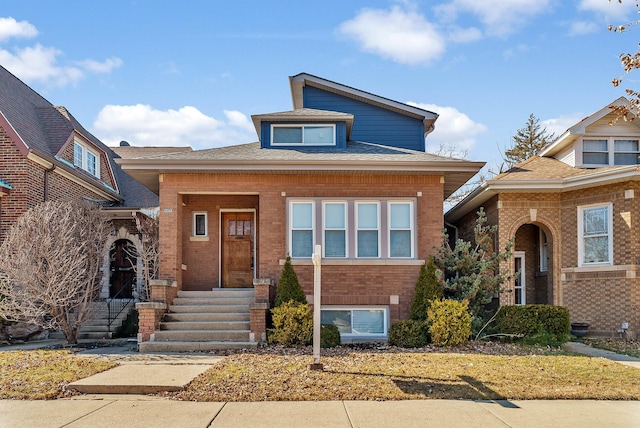 view of front of home featuring a shingled roof, entry steps, and brick siding