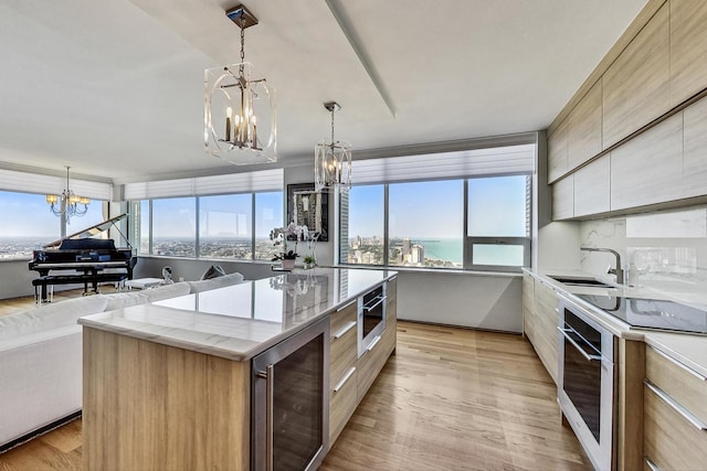 kitchen featuring wine cooler, a water view, stainless steel oven, a notable chandelier, and a large island