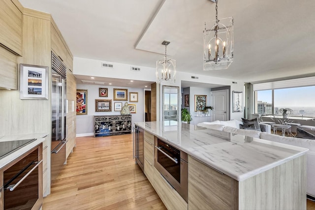 kitchen featuring a center island, wall oven, a notable chandelier, black electric stovetop, and light hardwood / wood-style floors