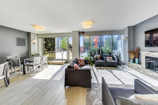 living room featuring a stone fireplace and light hardwood / wood-style floors