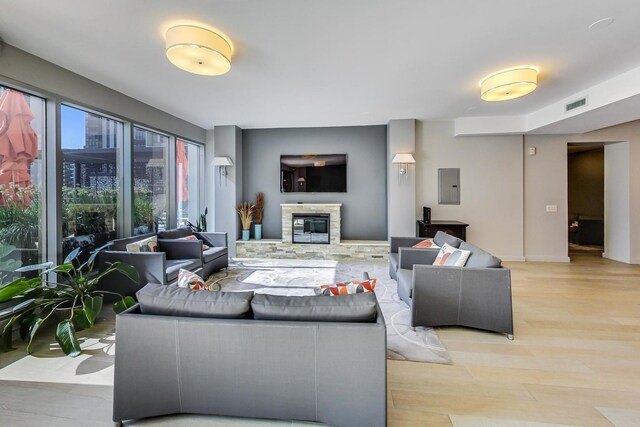 living room featuring a stone fireplace, electric panel, and light hardwood / wood-style floors