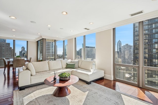 living area featuring expansive windows, a view of city, visible vents, and wood finished floors