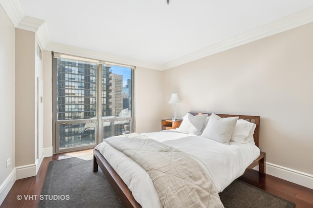 bedroom featuring baseboards, a view of city, wood finished floors, and crown molding