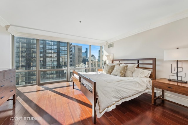 bedroom featuring visible vents, hardwood / wood-style flooring, floor to ceiling windows, a city view, and crown molding