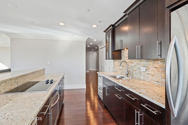 kitchen with dark wood-style flooring, ornamental molding, a sink, black electric stovetop, and stainless steel fridge