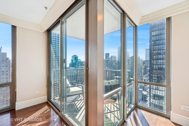 interior space with a wall of windows, crown molding, a view of city, and wood finished floors